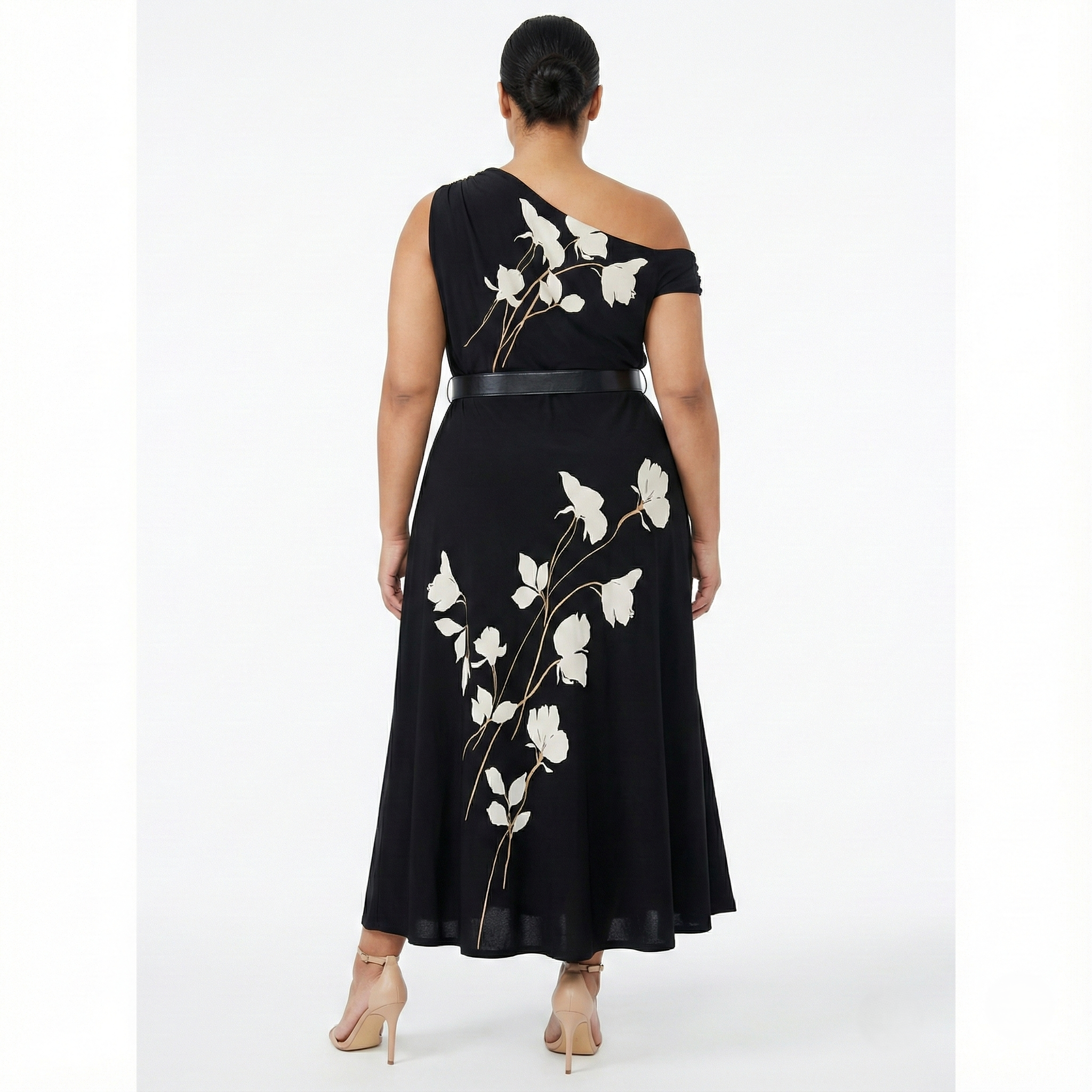 Back view of plus-size black one-shoulder maxi dress with white floral print and belted waist, featuring a flowing ankle-length skirt.