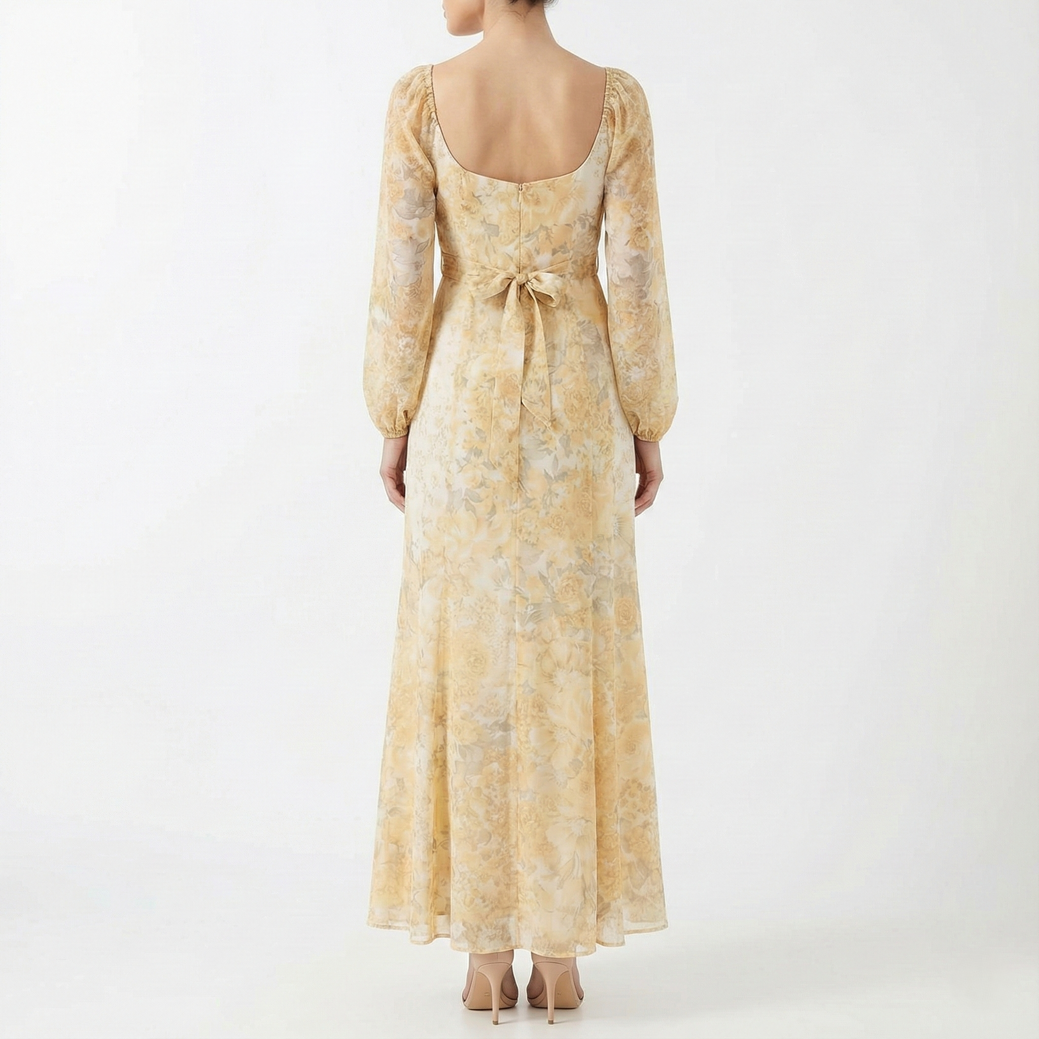 Back view of a women’s yellow floral maxi dress with low scoop back, waist tie detail, long sheer sleeves, and flowing full-length hem.