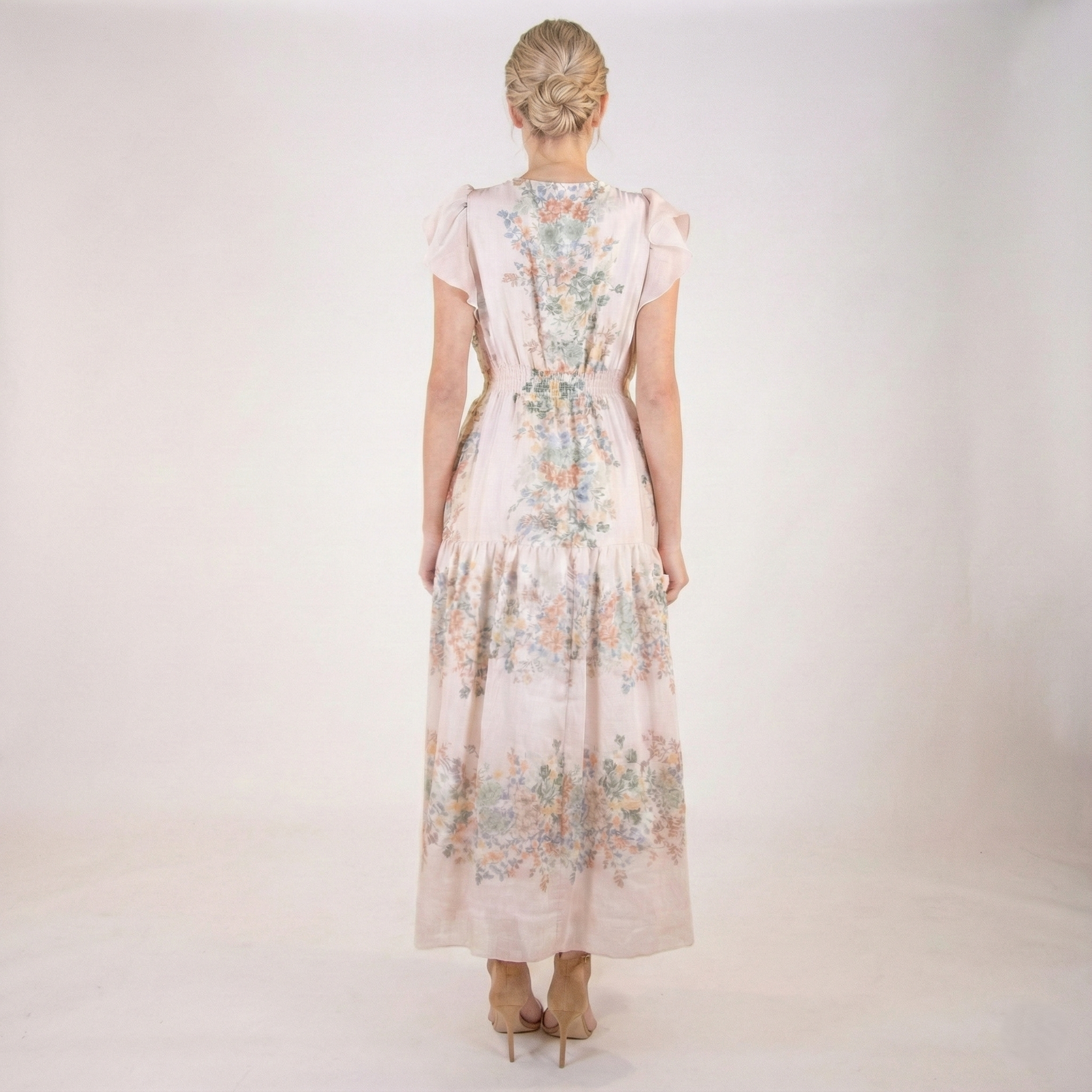 Full back view of blush pink floral chiffon maxi dress featuring flutter sleeves, smocked waist detail, soft floral print, and tiered maxi skirt.