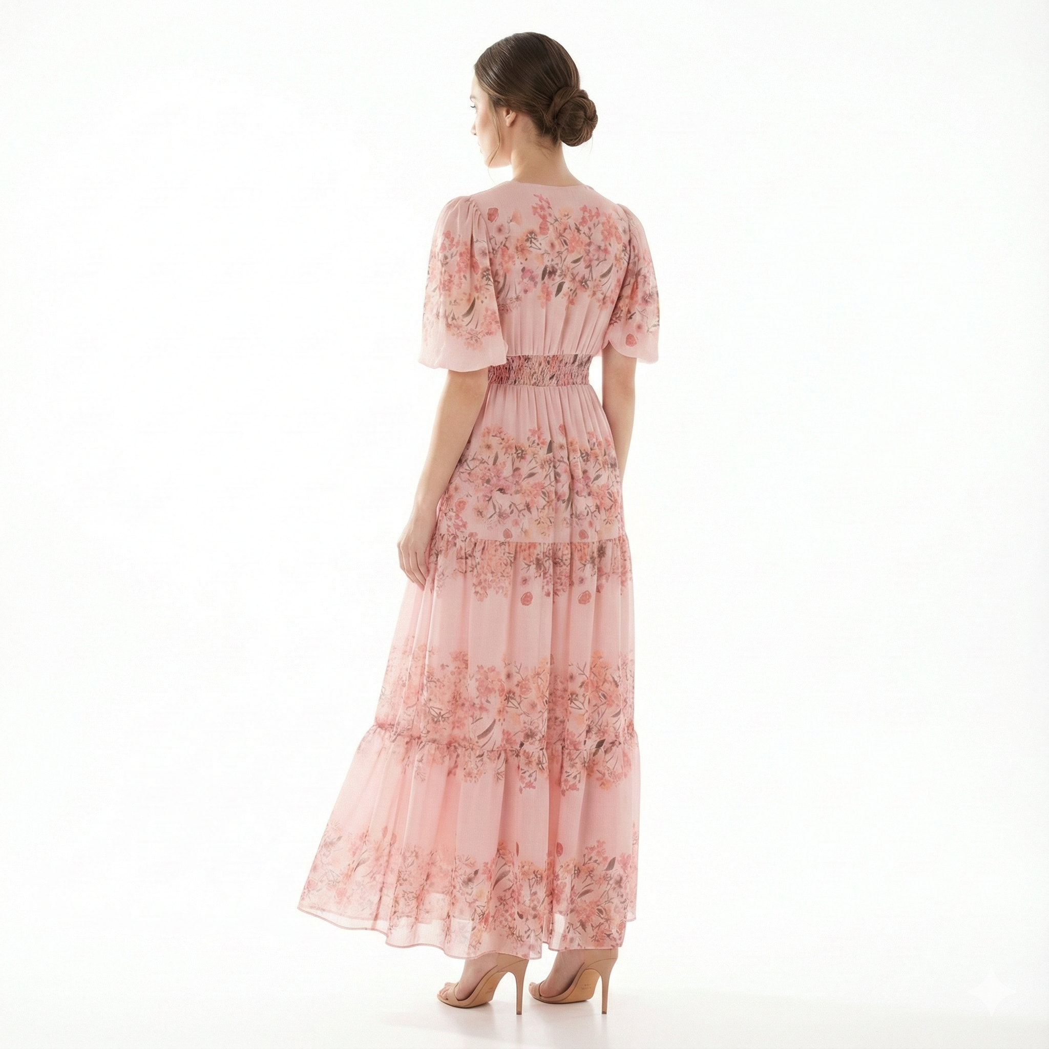 Back view of blush pink floral chiffon maxi dress with short puff sleeves, smocked waistband, and tiered ankle-length skirt.