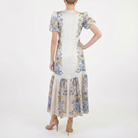 Back view of beige floral midi dress featuring puff sleeves, waist seam detail, and flowy tiered skirt.