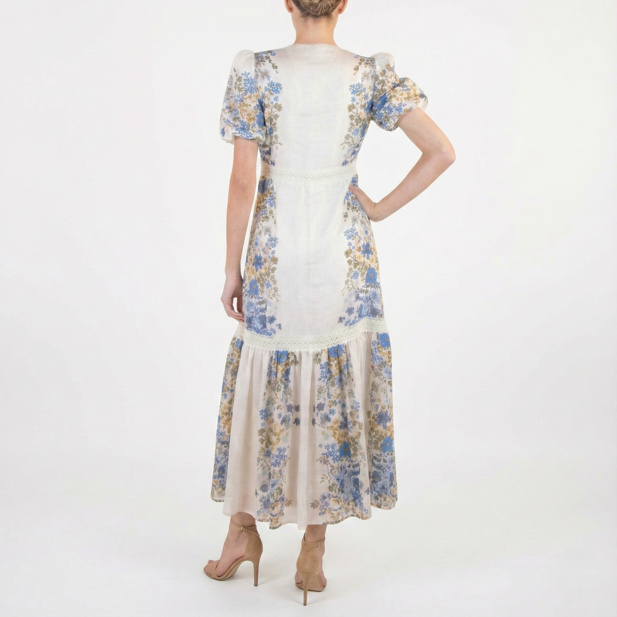 Back view of beige floral midi dress featuring puff sleeves, waist seam detail, and flowy tiered skirt.