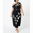 Plus-size black one-shoulder maxi dress with white floral print, belted waist, and flowing skirt, shown from the front on a model.