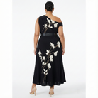 Back view of plus-size black one-shoulder maxi dress with white floral print and belted waist, featuring a flowing ankle-length skirt.
