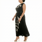 Side view of plus-size black one-shoulder maxi dress with white floral print, belted waist, and soft drape.