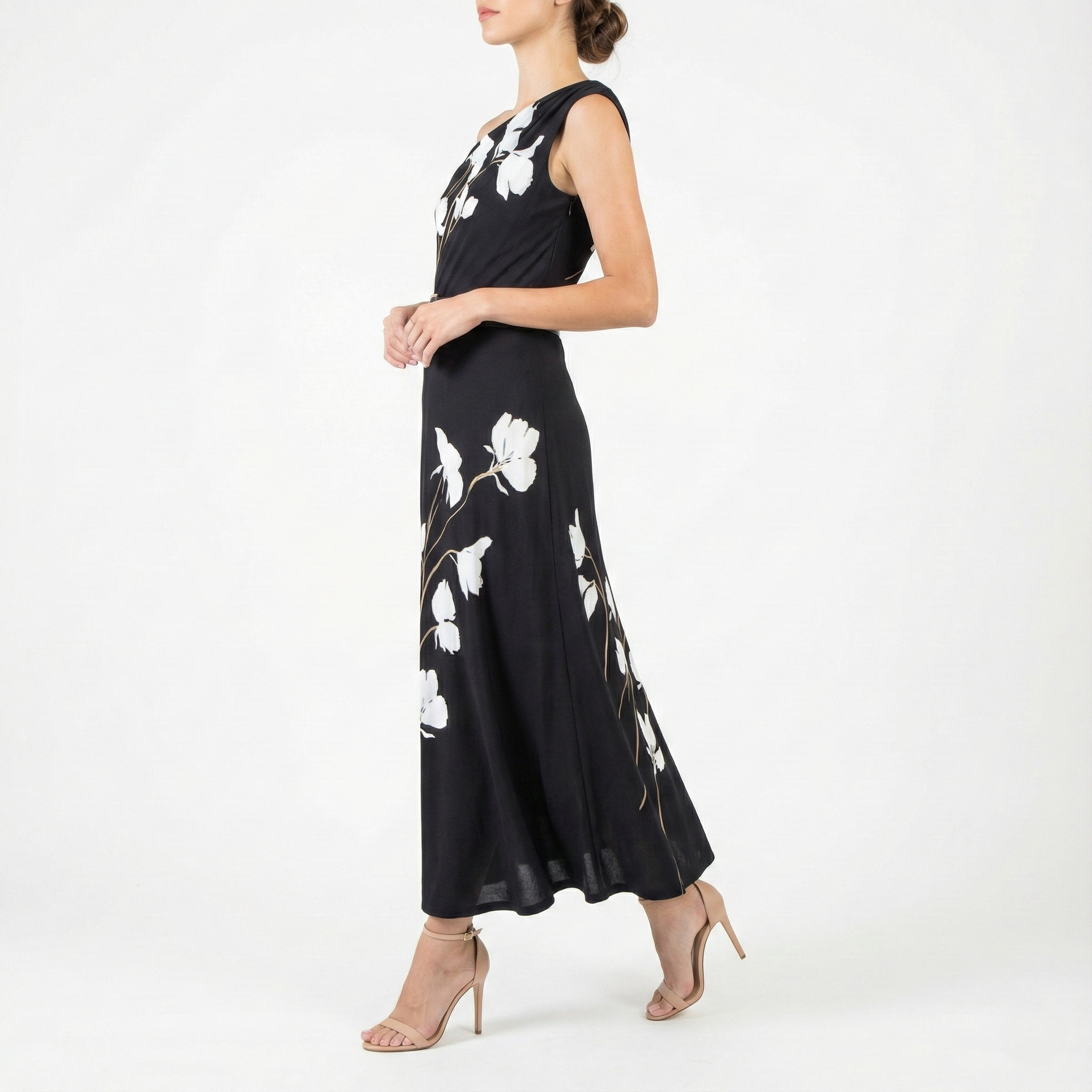 Side view of black one-shoulder midi dress featuring white floral print and flowing skirt, worn with nude ankle-strap heels.