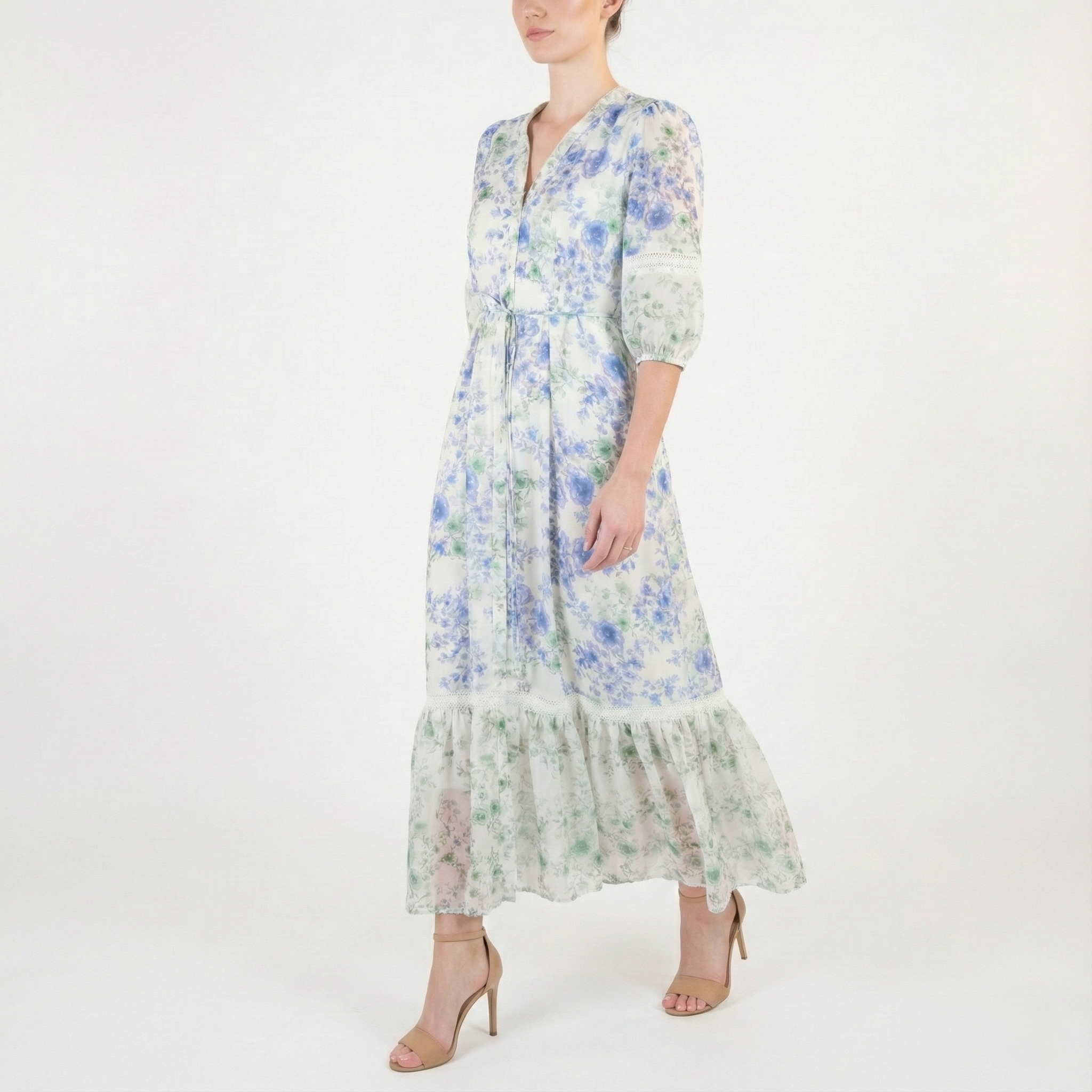 Side view of a light ivory floral midi dress with blue and green flowers, V-neck, sheer three-quarter sleeves, tie waist, and flowing ruffled hem.