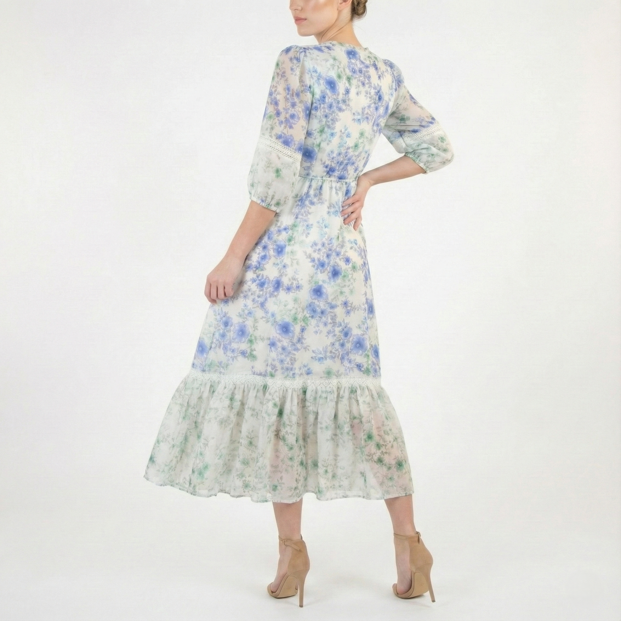 Back view of a light ivory midi dress with blue and green floral print, fitted waist, sheer three-quarter sleeves, and ruffled hem.
