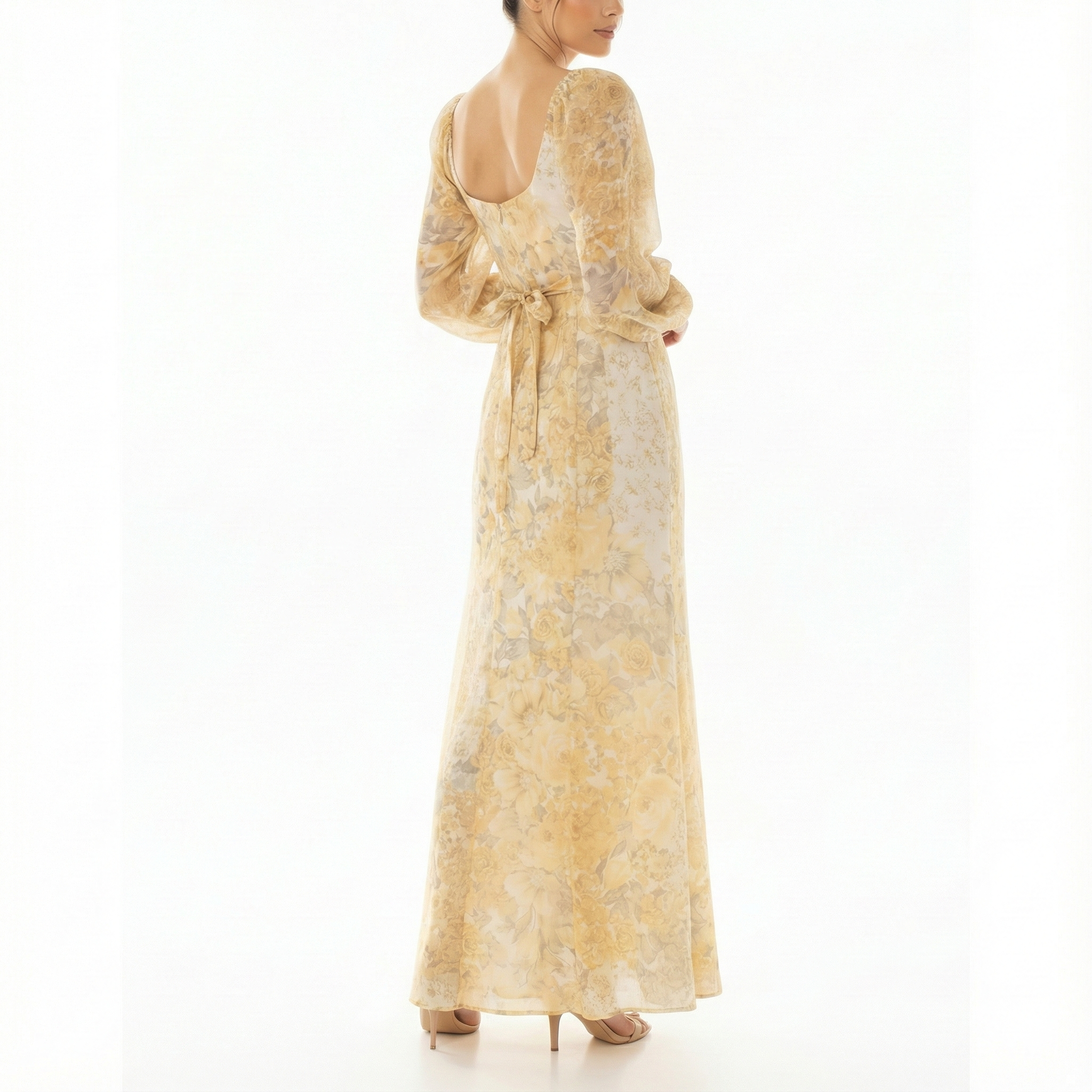 Angled back view of a women’s yellow floral maxi dress with low scoop back, adjustable tie waist bow, long sheer sleeves, and floor-length skirt.