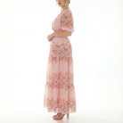 Side view of blush pink floral chiffon maxi dress featuring short puff sleeves, flowing tiered skirt, and lightweight semi-sheer fabric.