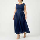 Plus-size navy blue sleeveless maxi dress with empire waist and airy chiffon skirt, showing contrast stitch detailing, angled front view.