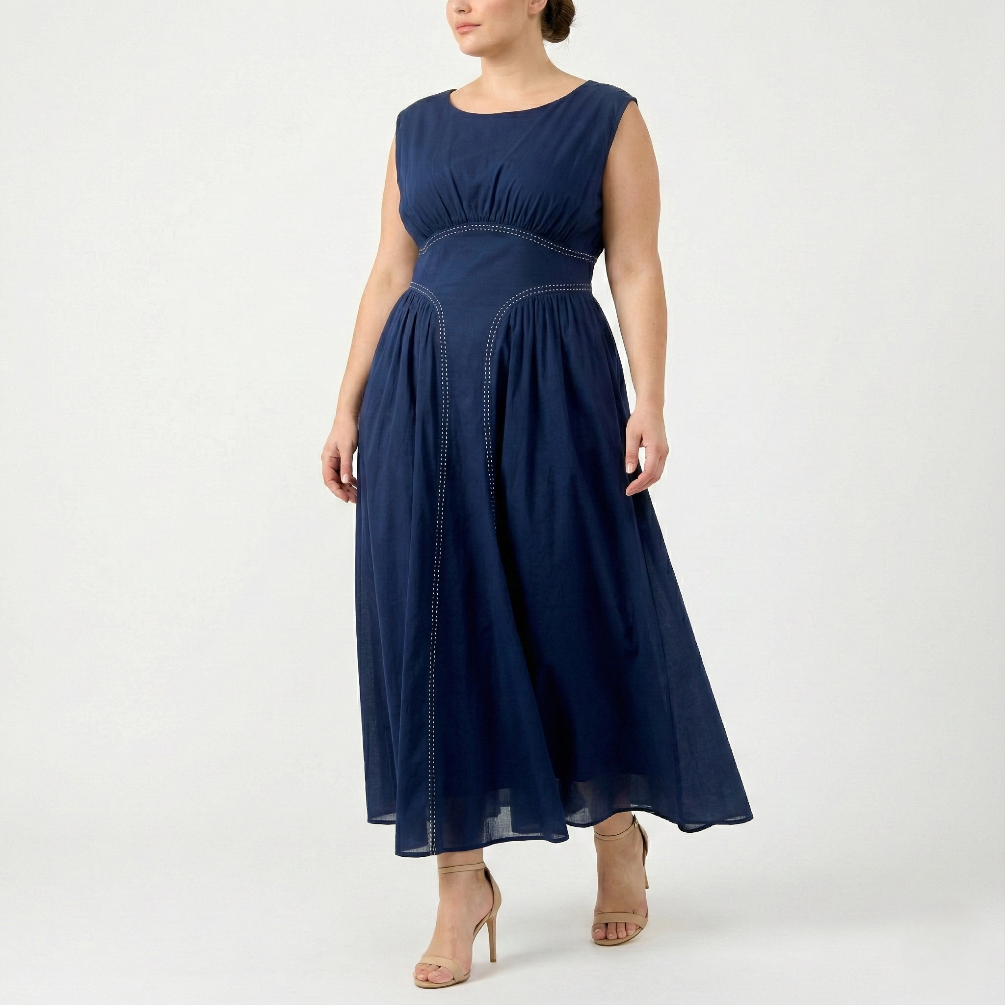 Plus-size navy blue sleeveless maxi dress with empire waist and airy chiffon skirt, showing contrast stitch detailing, angled front view.