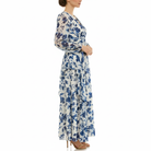 Side angled view of women’s blue and white floral chiffon maxi dress featuring long sheer sleeves, V-neck wrap bodice, empire waist, and tiered flowing skirt.