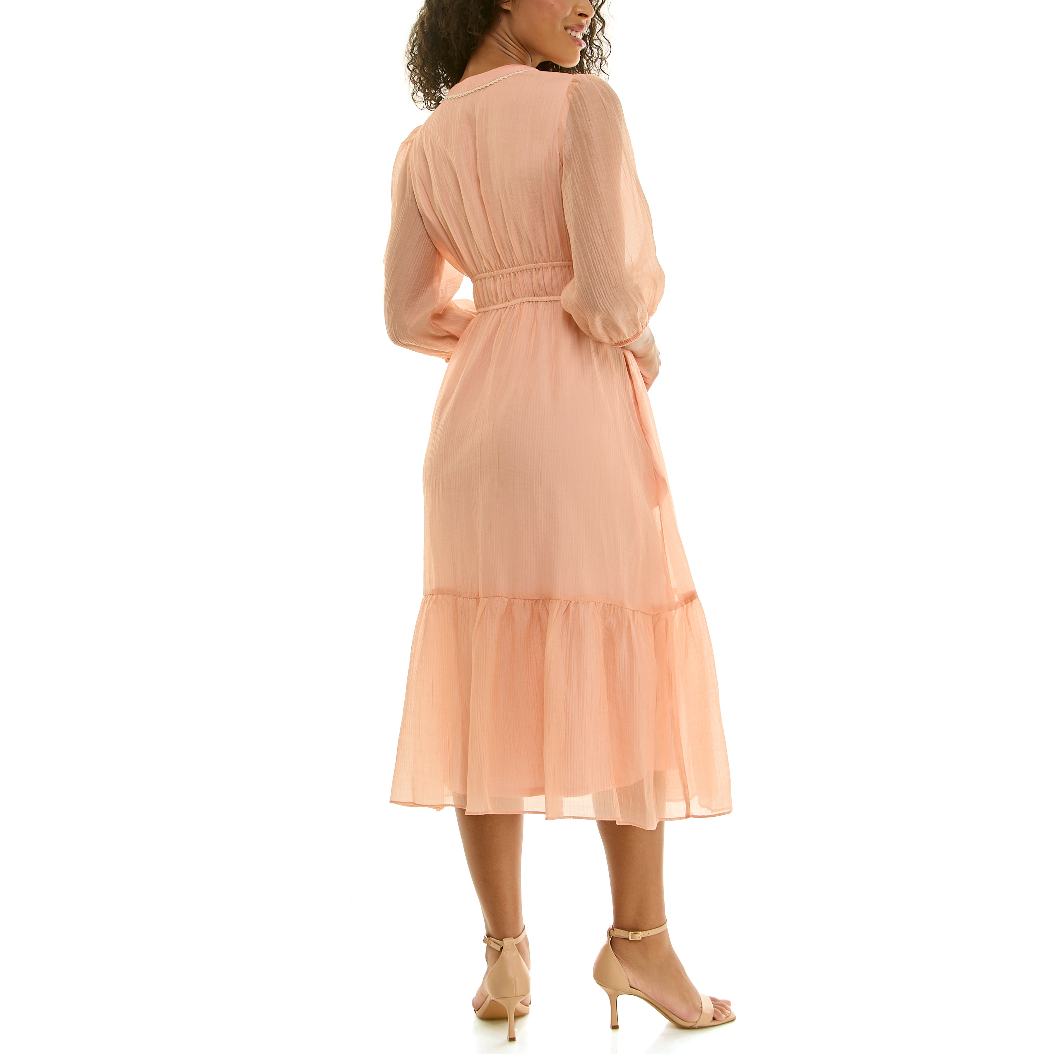 Back view of a peach sheer midi dress showing a gathered elastic waist, flowing tiered skirt, and three-quarter sleeves, worn with nude ankle-strap heels.