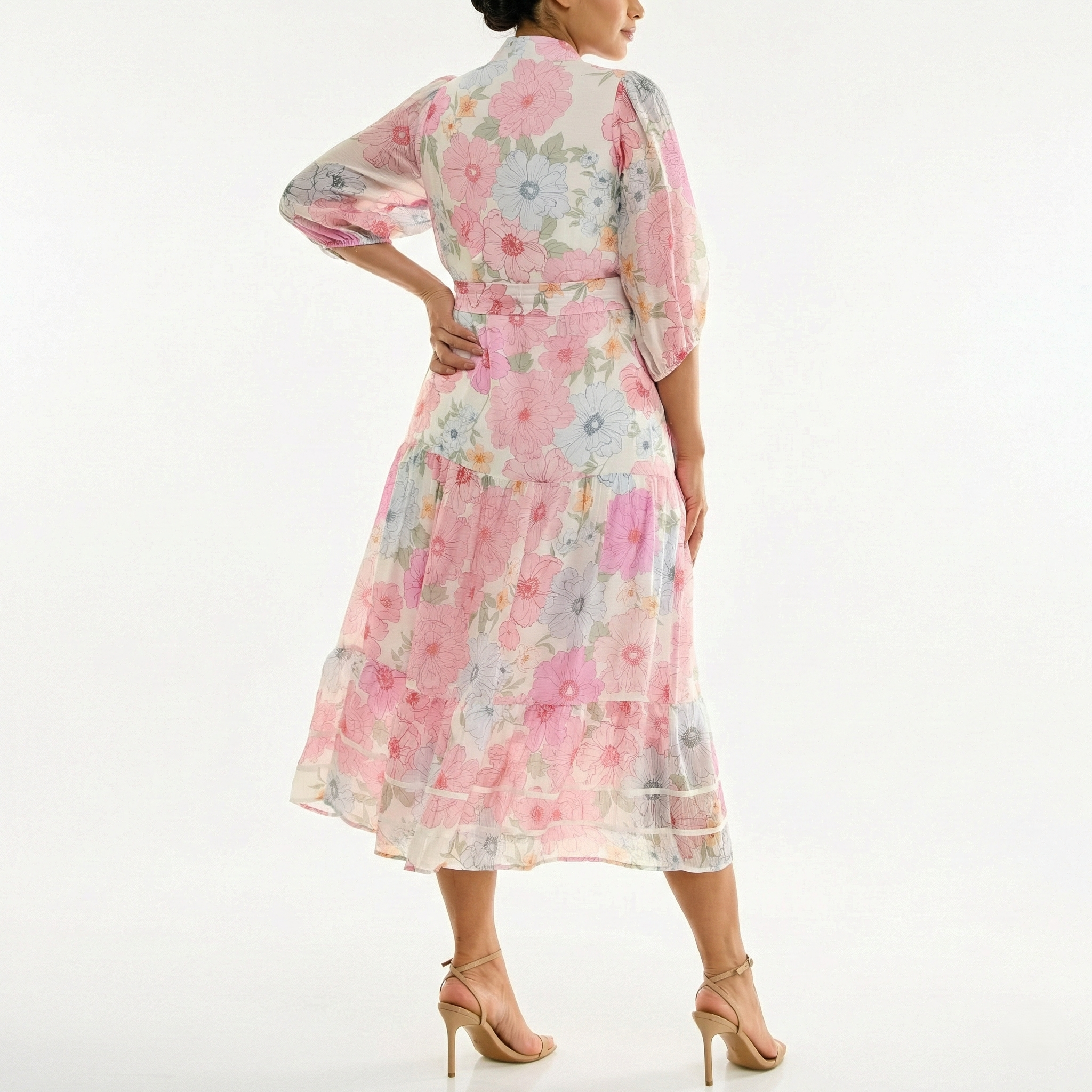 Model wearing a sheer, pastel floral midi dress with elbow-length sleeves and a tie belt, shown from the back, paired with nude high-heel sandals