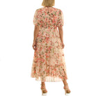 Back view of a woman wearing a light pink, floral-print midi dress with short puff sleeves, a fitted elastic waist, tiered skirt, and nude high-heeled sandals against a white background.