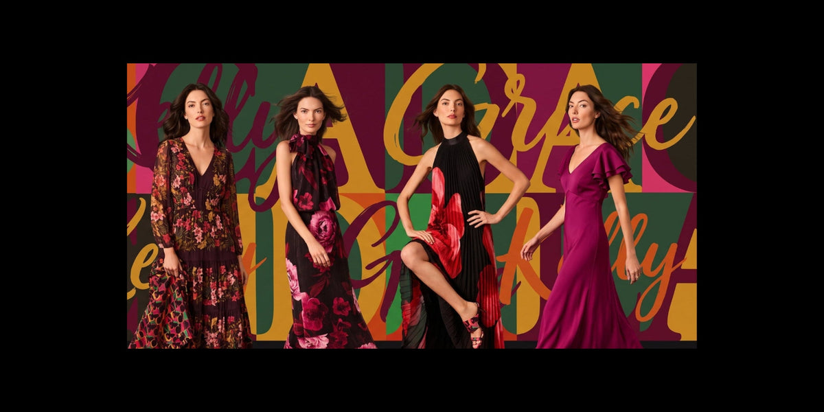 Four women modeling long dresses in a stylized studio scene with a multicolored graphic background featuring the words 'Kelly' and 'Grace'. The dresses include floral prints and solid colors like burgundy, black, and magenta.